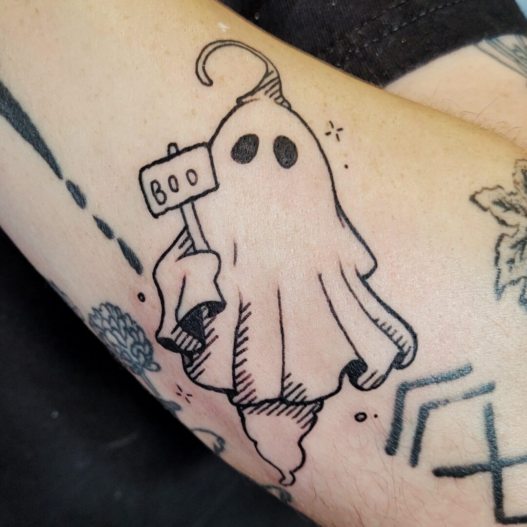 A person with a tattoo of a ghost holding a sign.
