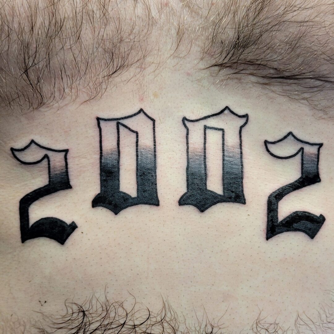 A tattoo of the year 2 0 0 2 is shown.