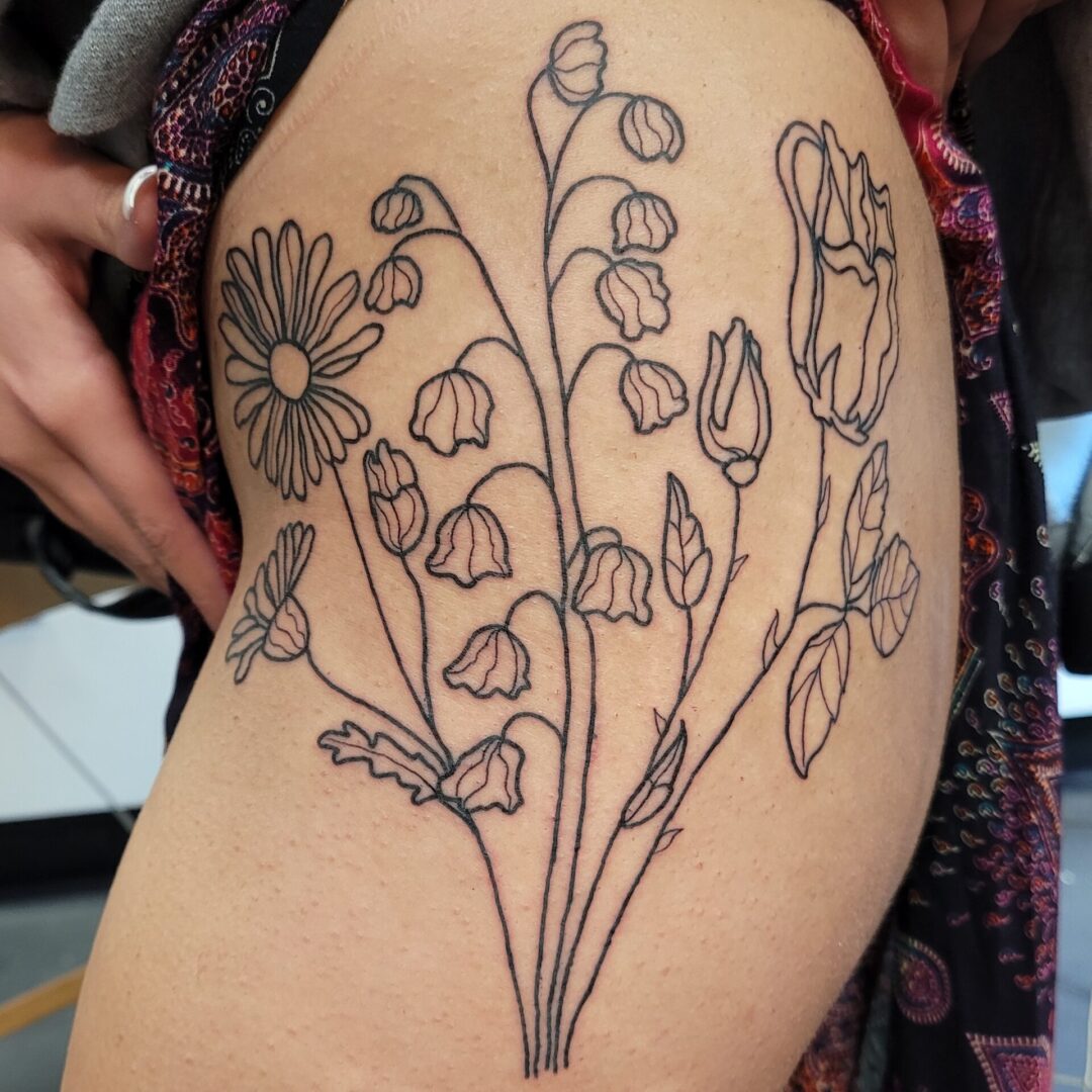 A woman with a tattoo of flowers on her thigh.